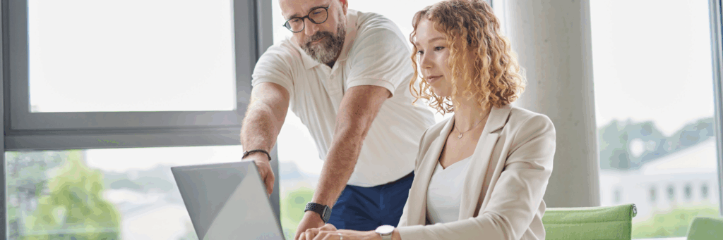 Team members collaborating at a laptop in a modern office, illustrating how a platform company enables efficient digital workflows.