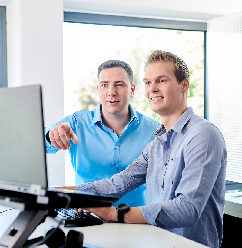 d.velop employees in front of a desktop screen