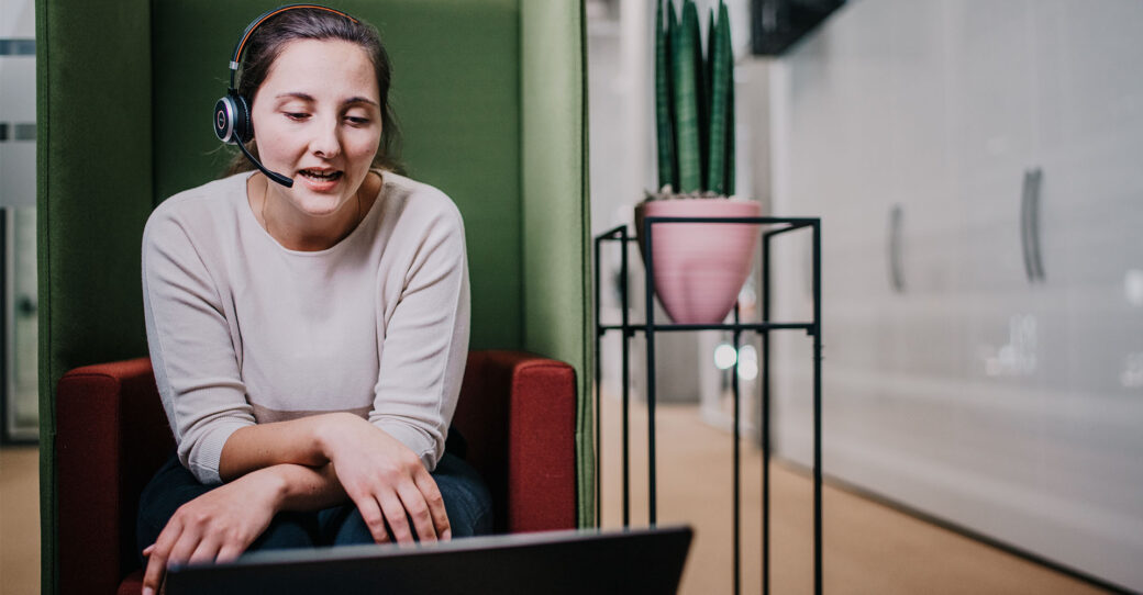 Employee working with a headset on in front of a laptop