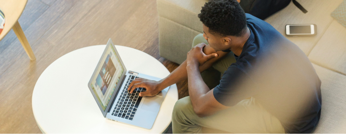 male sitting with laptop and phone