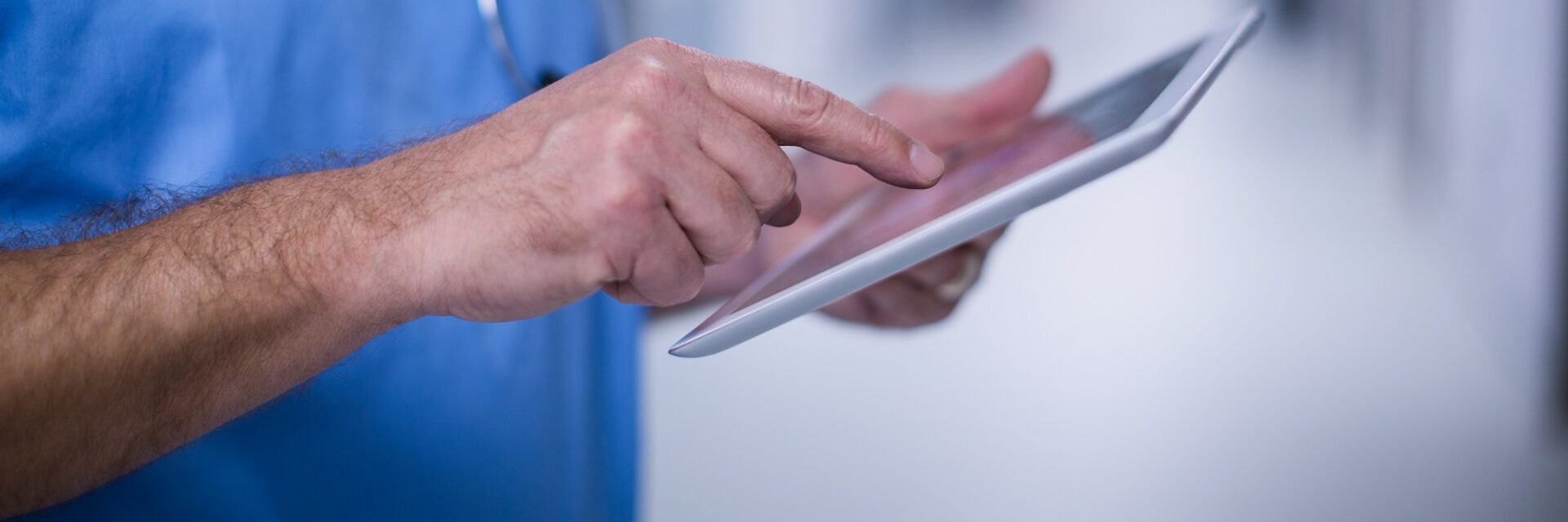 Mid section of male surgeon using digital tablet in operation room at hospital